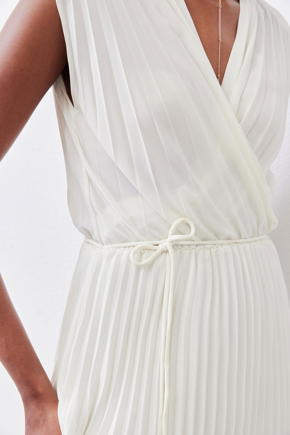 Ivory pleated wrap dress detail: V-neck bodice and tied waist with drawstring.