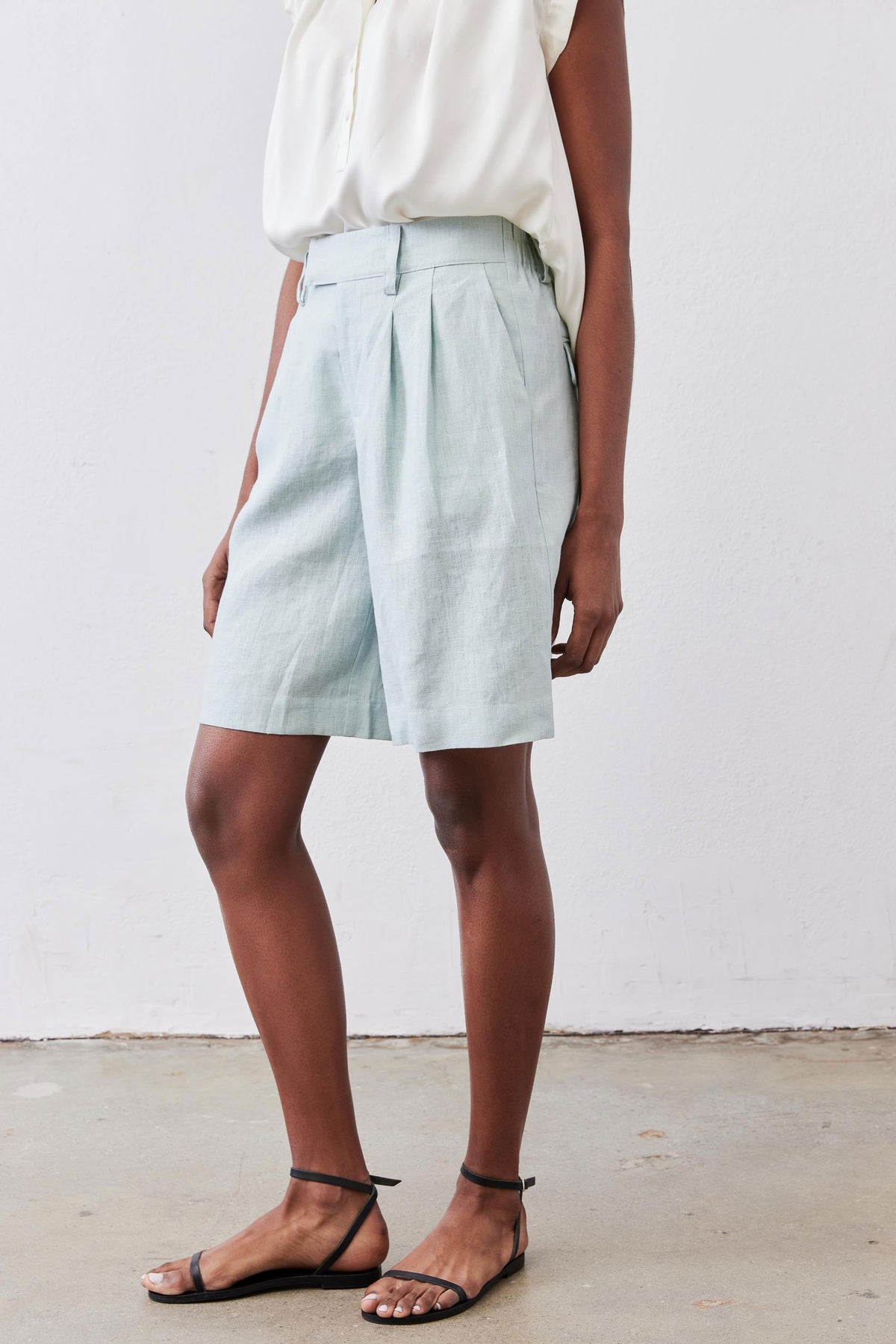 Mint pleated bermuda shorts, side view with pleated waistband and cuffed hem