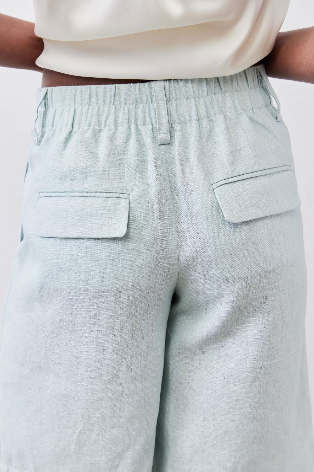 Mint pleated bermuda shorts close-up showing two patch pockets