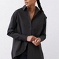 Black asymmetric button-down shirt with pointed collar and button front, long sleeves.