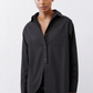 Black asymmetric button-down shirt with chest pocket, pointed collar, hip-length hem.
