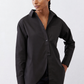 Black asymmetric button-down shirt with pointed collar and button placket, long sleeves.