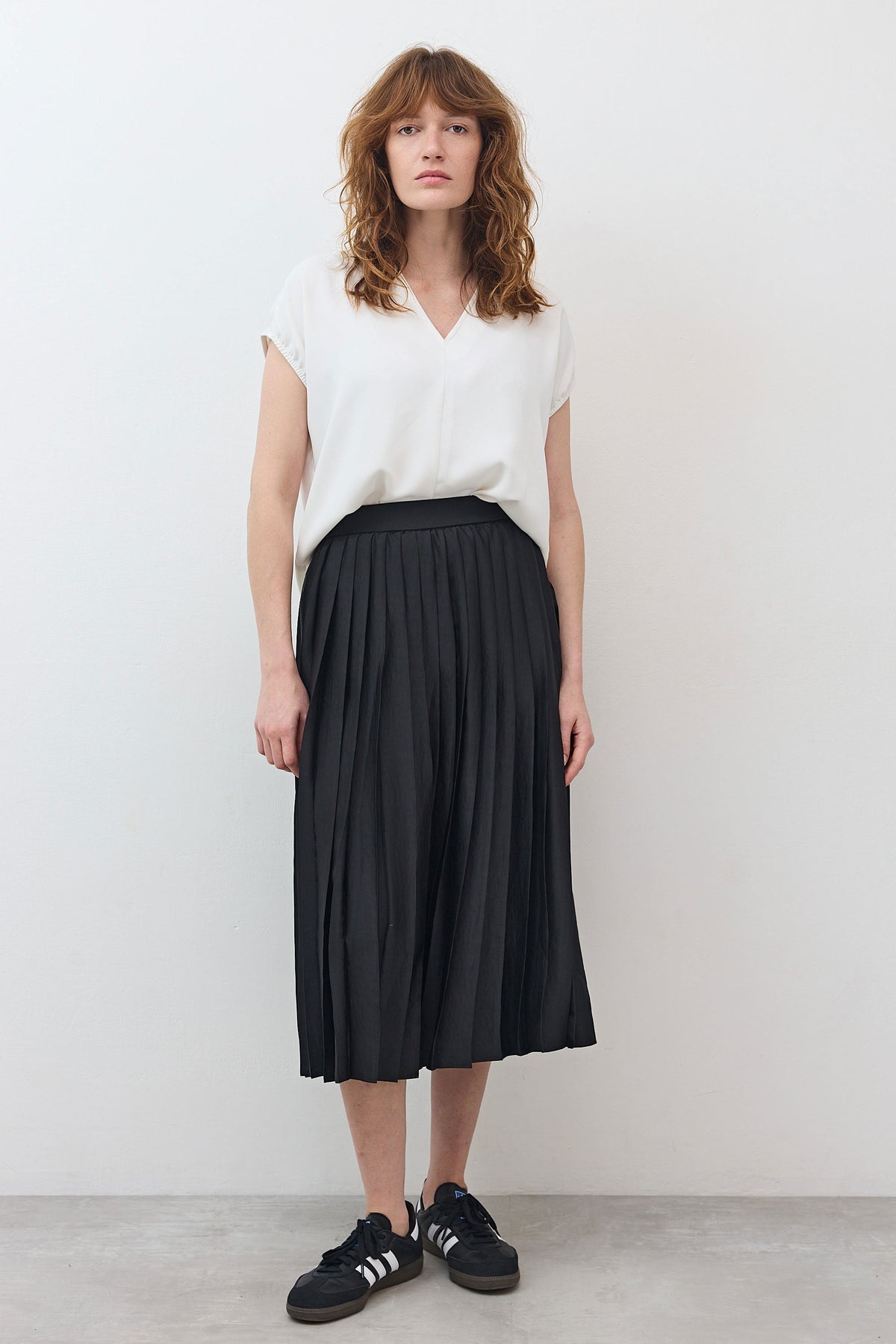 Black pleated skirt with elastic waistband, mid-calf length, front view