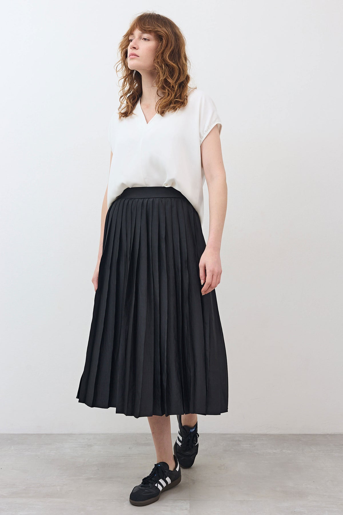 Black pleated skirt with elastic waistband, mid-calf length, side view