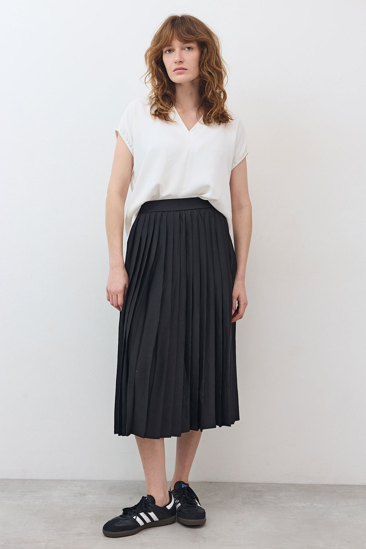 Black pleated skirt with elastic waistband, mid-calf length, front view