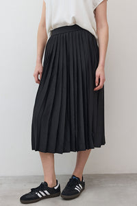 Black pleated skirt close-up, elastic waistband and vertical pleats, mid-calf