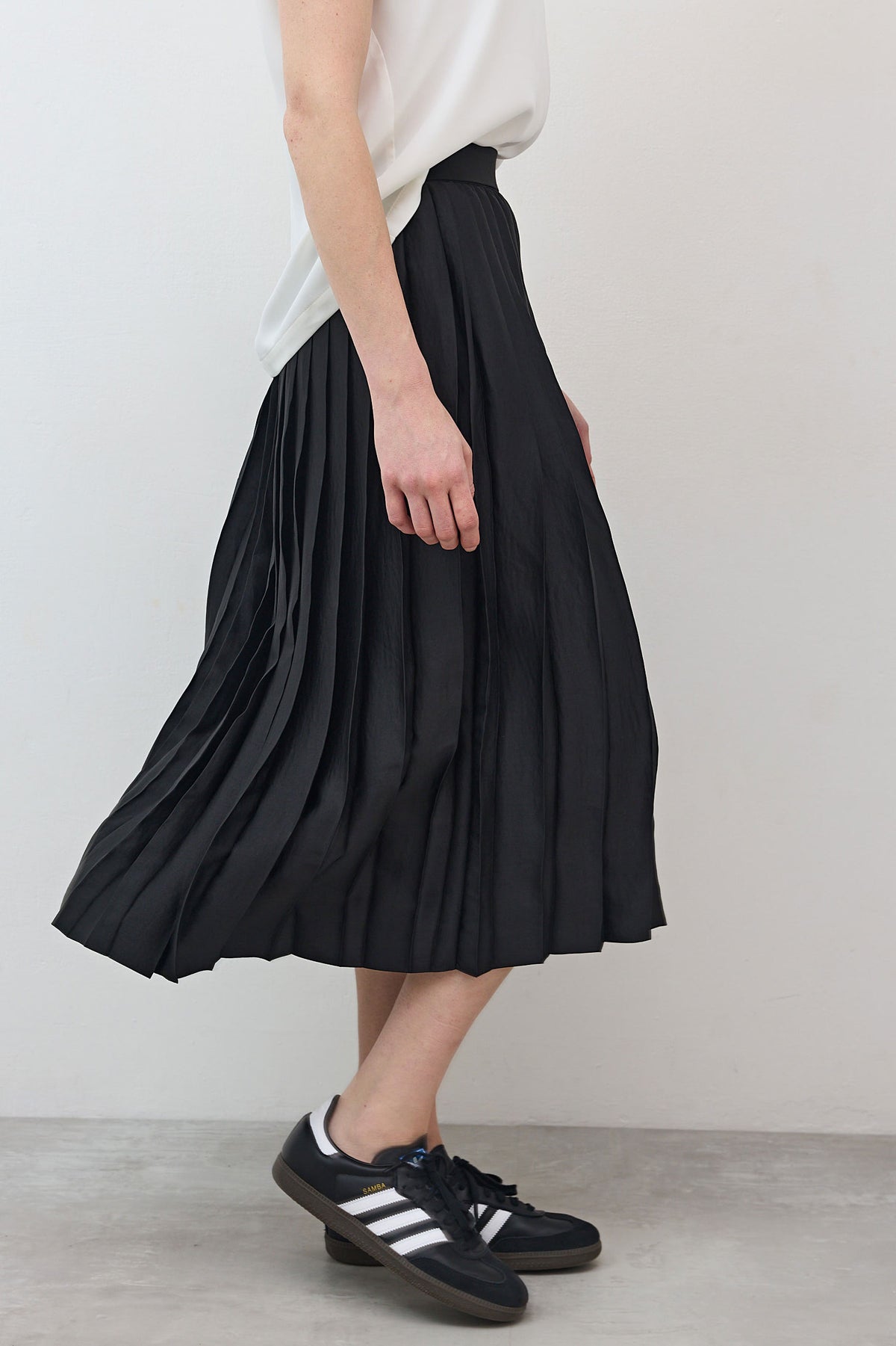 Black pleated skirt lower half with vertical pleats, elastic waistband at top