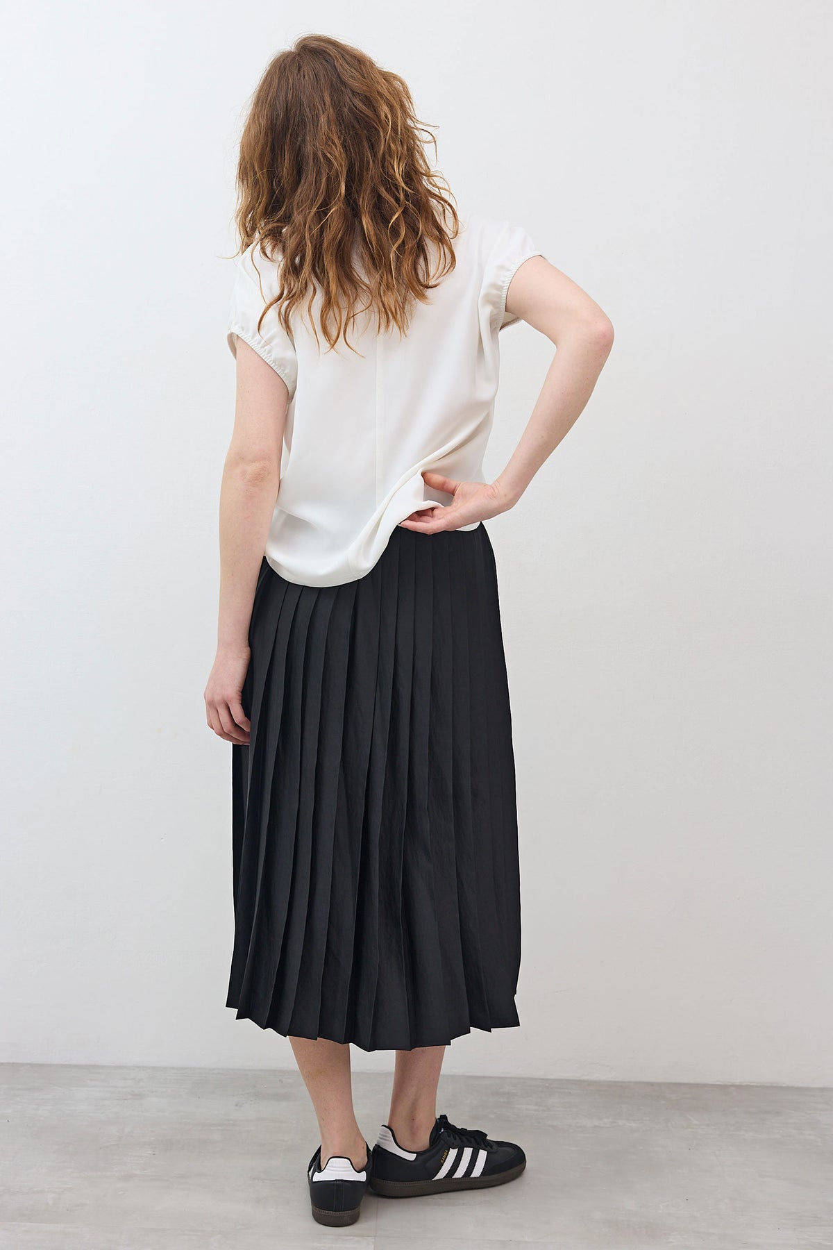 Black pleated pull-on skirt with gathered elastic waistband, mid-calf length