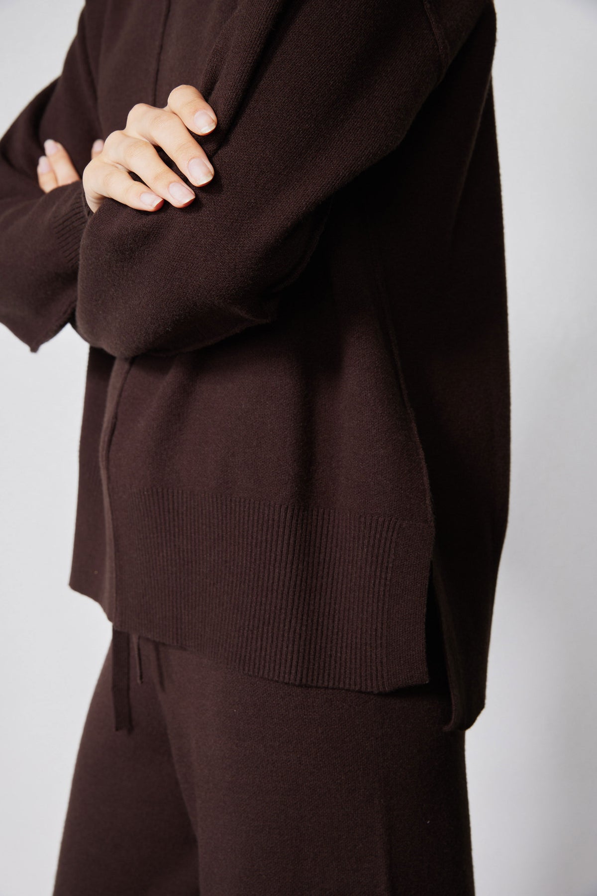 Chocolate plum wide-leg pants with ribbed hem and sweater hem overlap, close-up