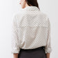 White tunic back view with small black dot print, button closure, and gathered cuffs
