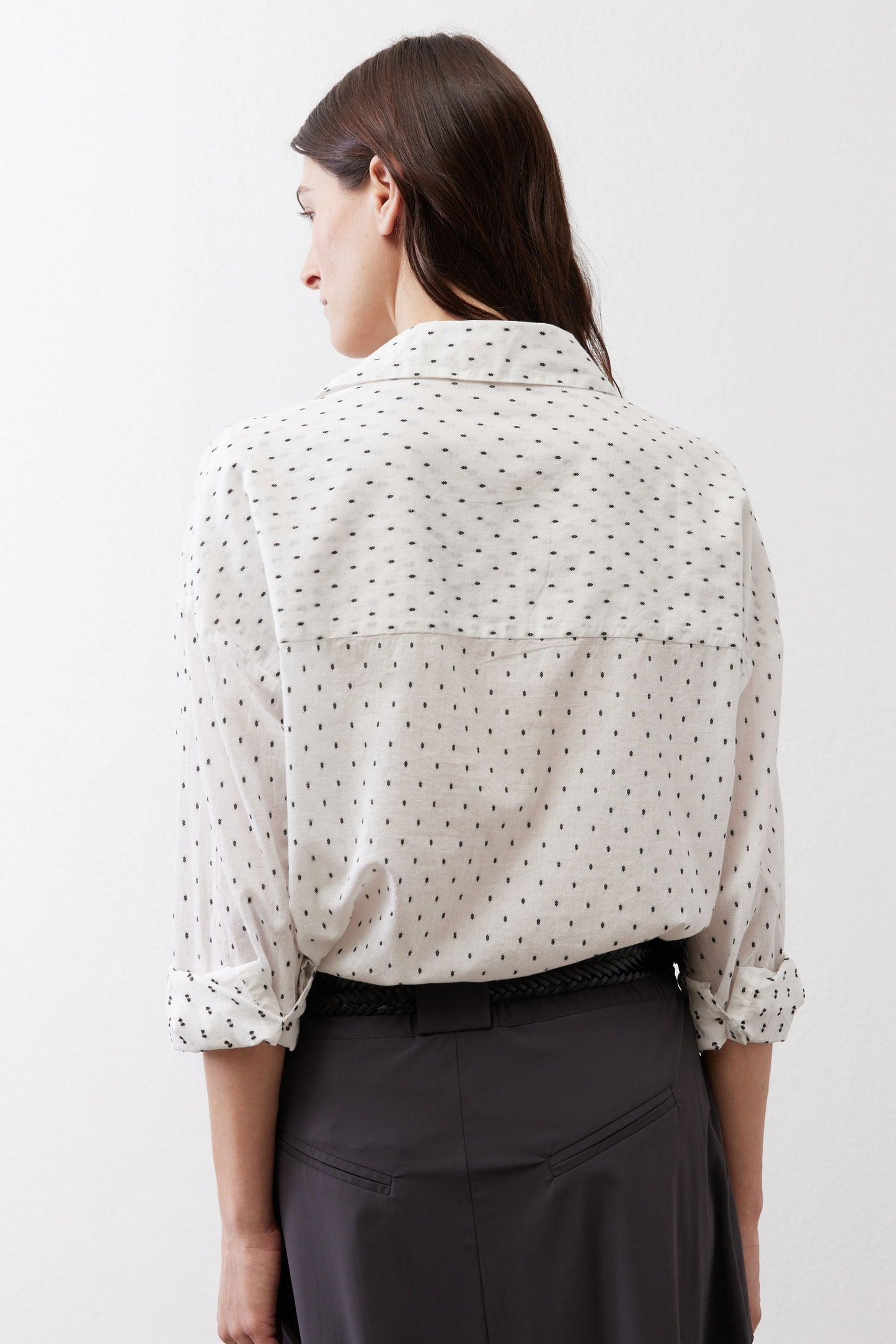 White tunic back view with small black dot print, button closure, and gathered cuffs