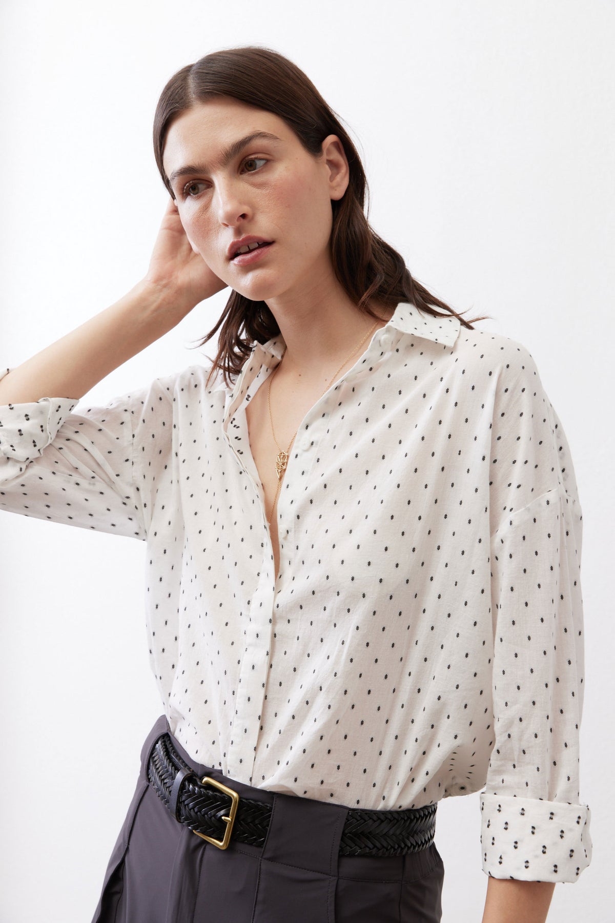 Close three-quarter view of white tunic with black dot print, open collar, button placket