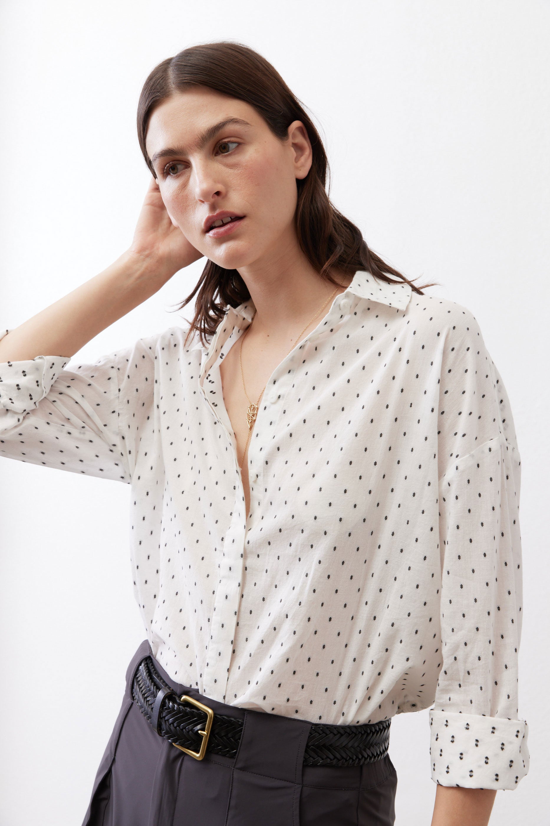 White tunic with black dot pattern, open collar, and long sleeves gathered at cuffs