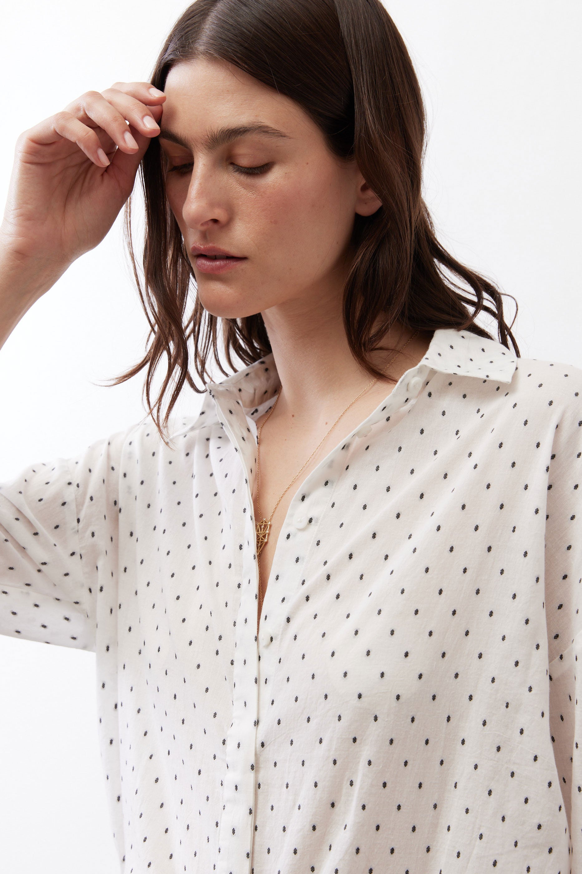 White tunic close-up with small black dots, open collar, and buttoned front