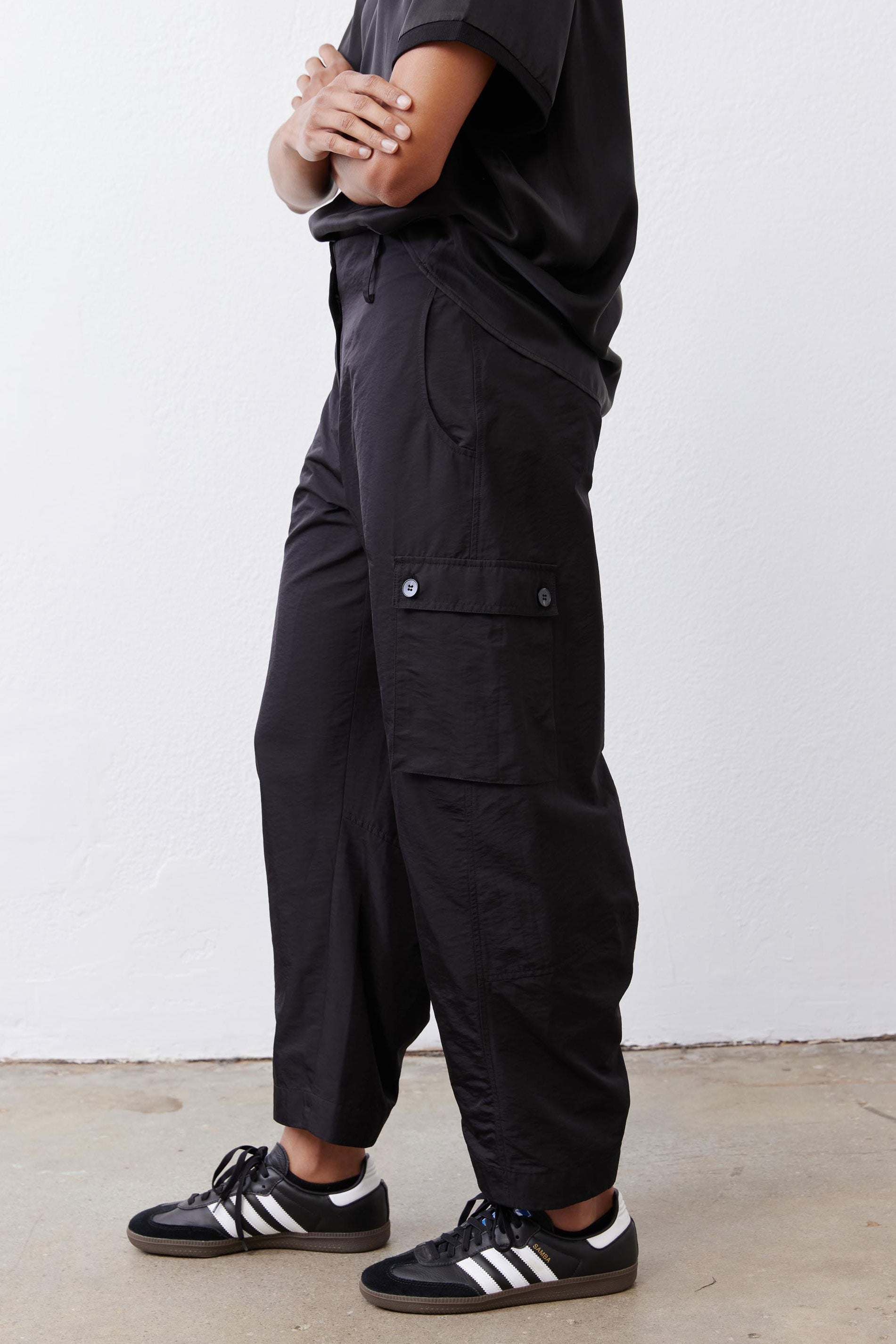 Black cargo barrel pants with flap pocket detail at the thigh and ankle cuffs