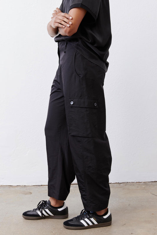 Black cargo barrel pants with flap pocket detail at the thigh and ankle cuffs