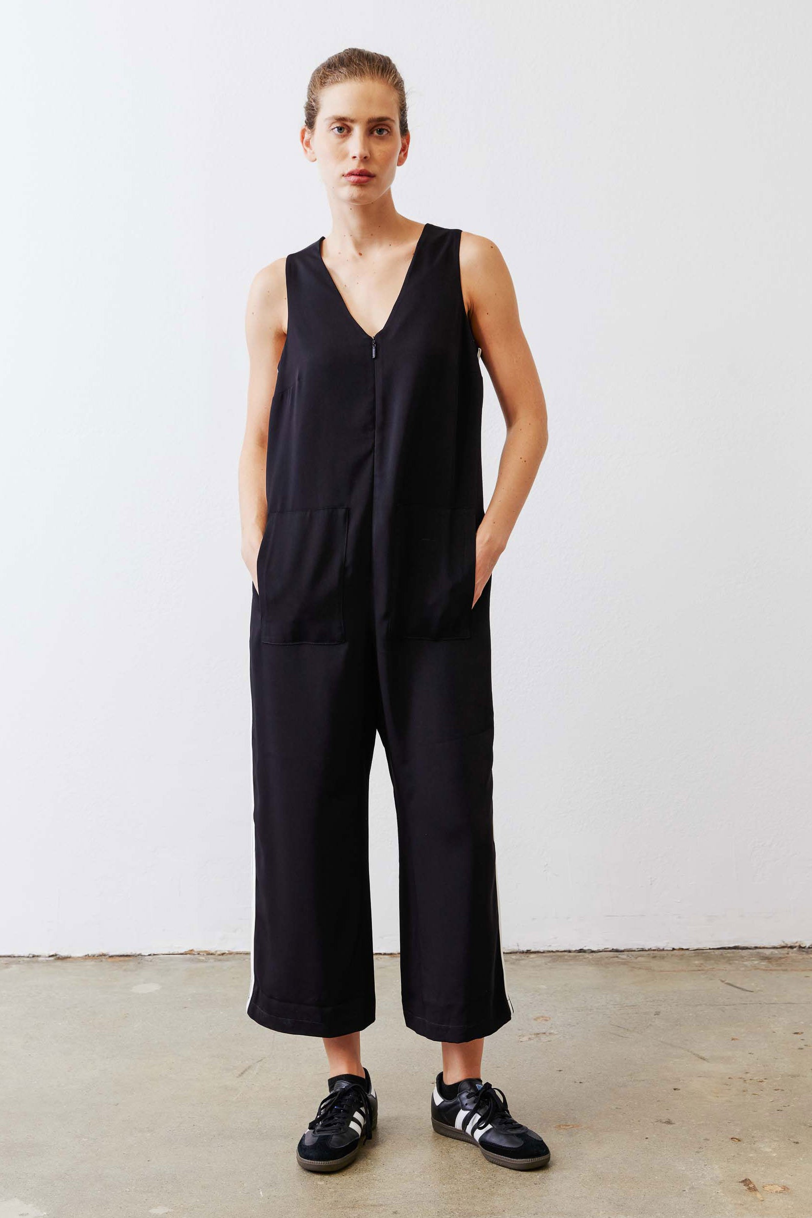 Black relaxed wide-leg sleeveless jumpsuit with V-neck and white side stripe, full front
