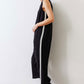 Black relaxed wide-leg sleeveless jumpsuit with V-neck and white side stripe, leaning view
