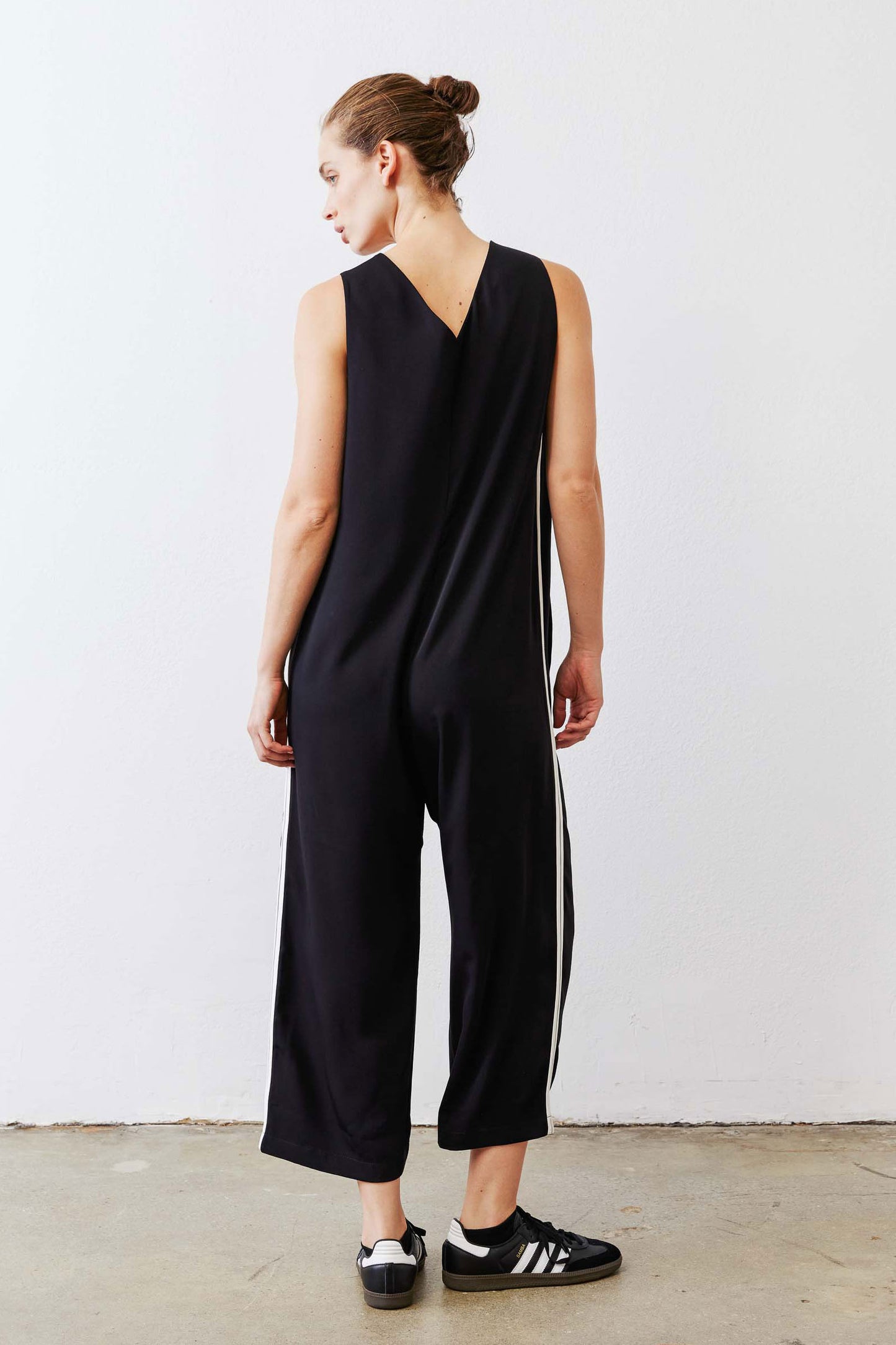 Black relaxed wide-leg sleeveless jumpsuit with white side stripe, back view