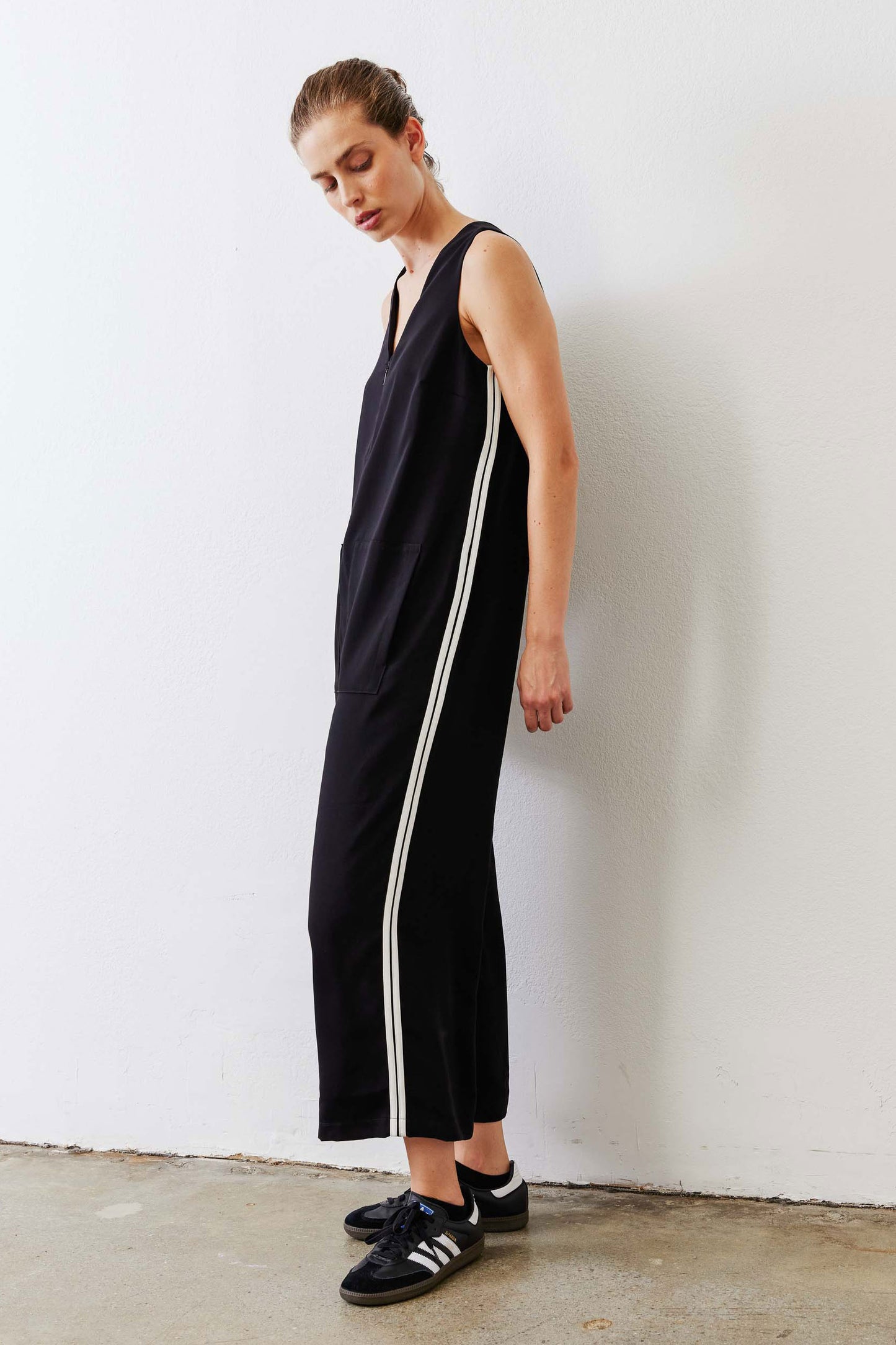 Black relaxed wide-leg sleeveless jumpsuit with V-neck and white side stripe, side view