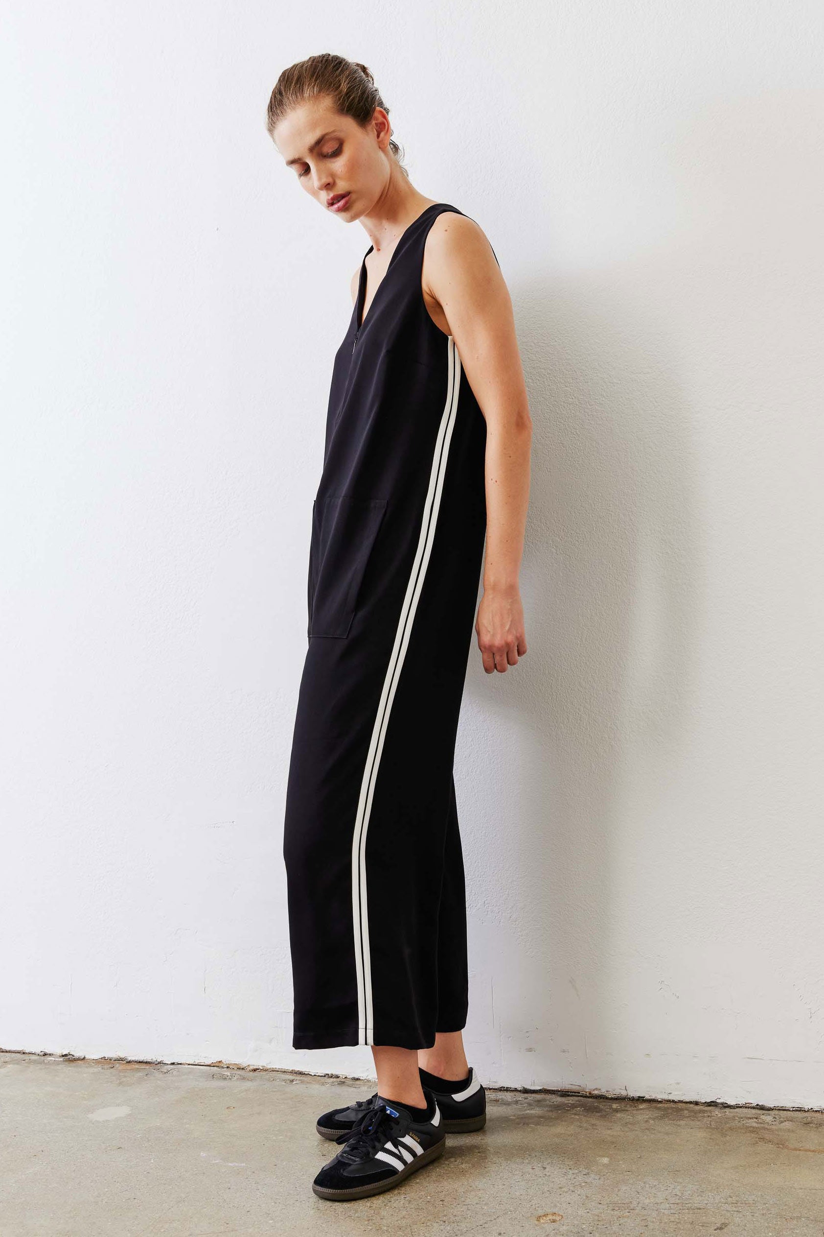 Black relaxed wide-leg sleeveless jumpsuit with V-neck and white side stripe, side view