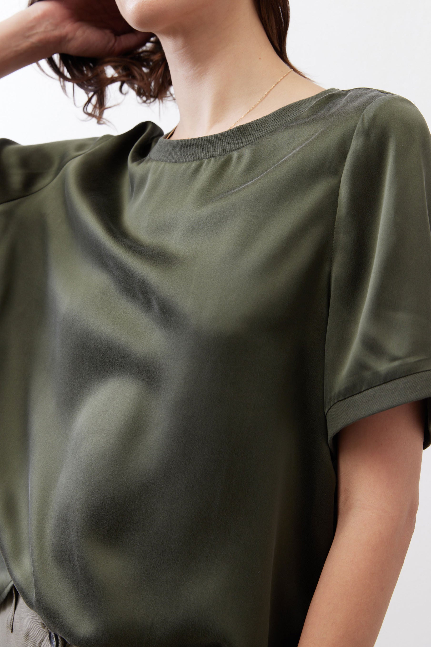 Forest green silk top close-up, smooth drape and crew neckline detail