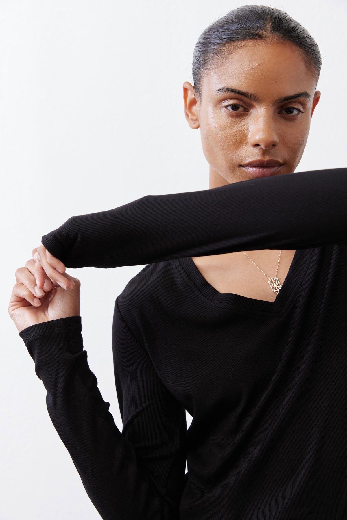 Black ribbed long-sleeve V-neck top, neckline close-up with extended arm