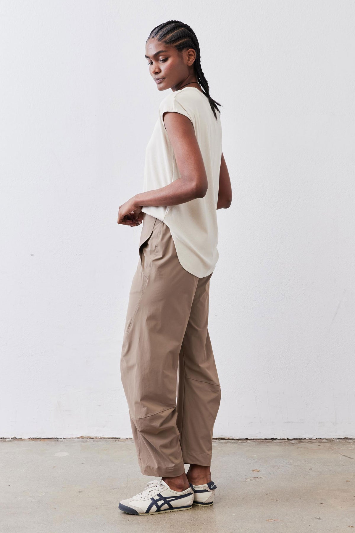 Light cream short-sleeve ribbed tee in side view, draped over pants