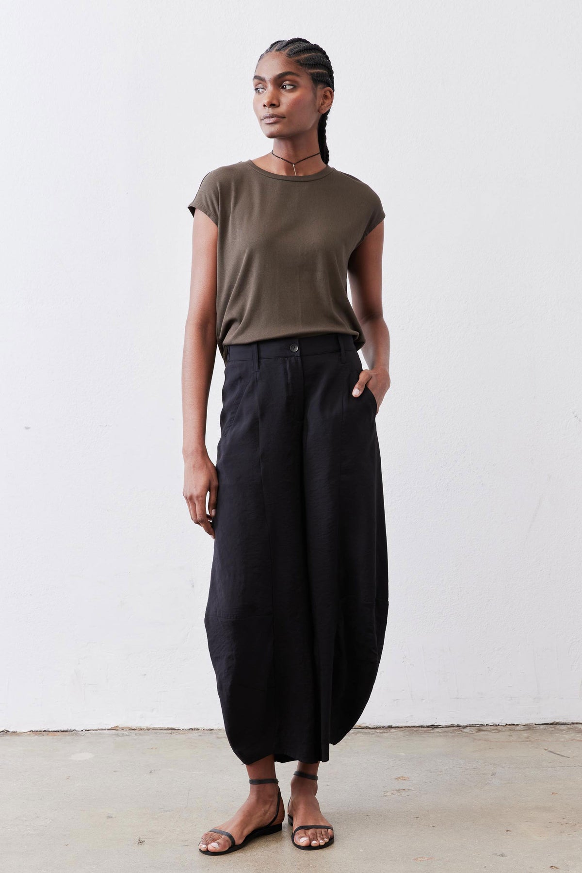Olive crewneck short-sleeve tee with loose drape, tucked hem over dark pants