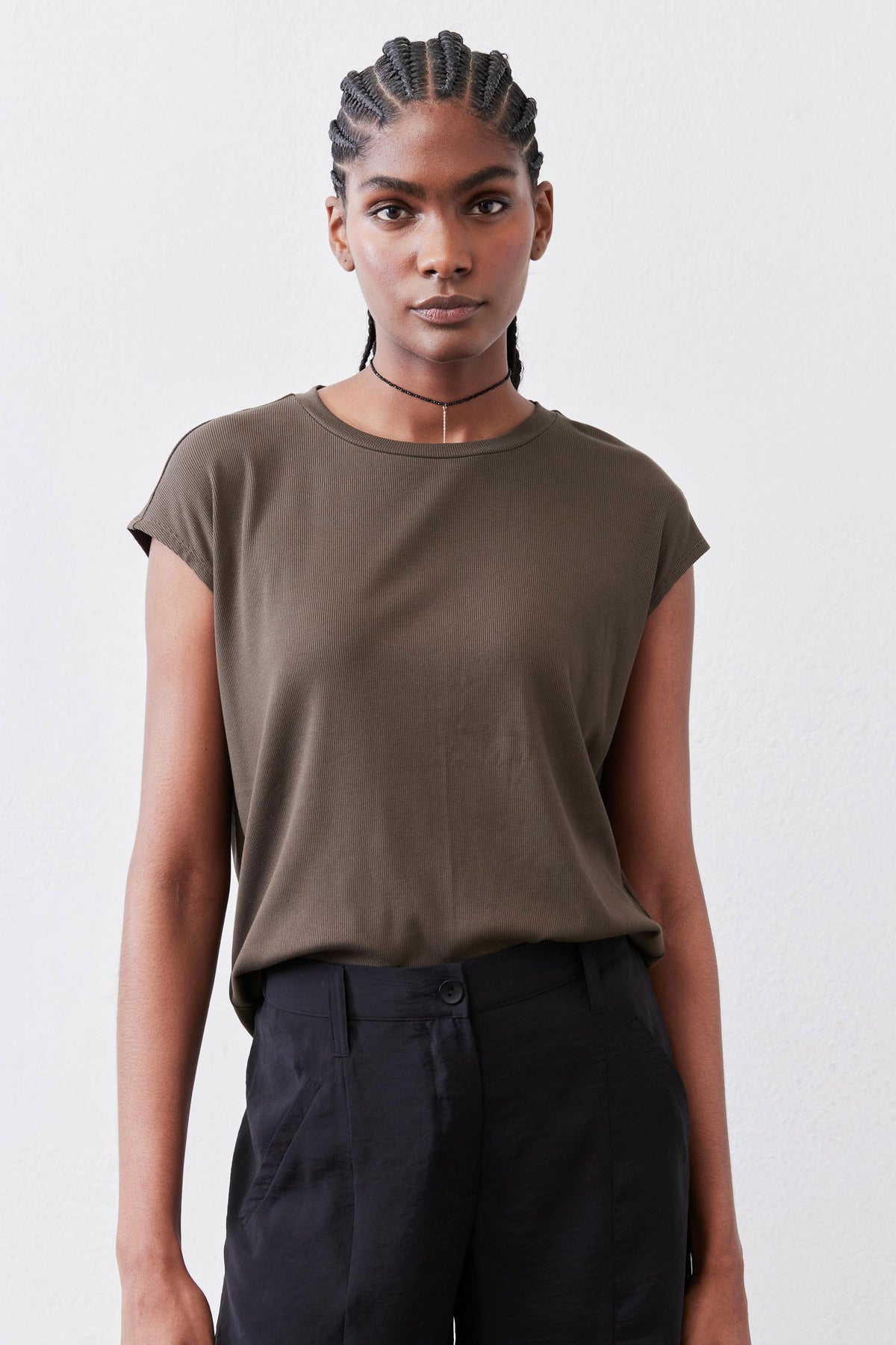 Olive crewneck short-sleeve tee worn over dark high-waisted pants