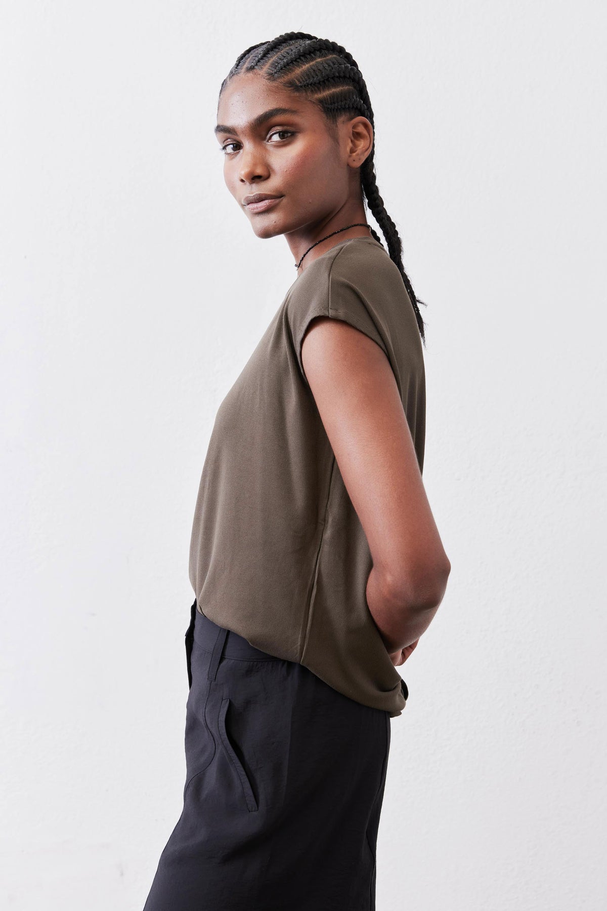 Olive crewneck short-sleeve tee, side view with relaxed fit over dark pants