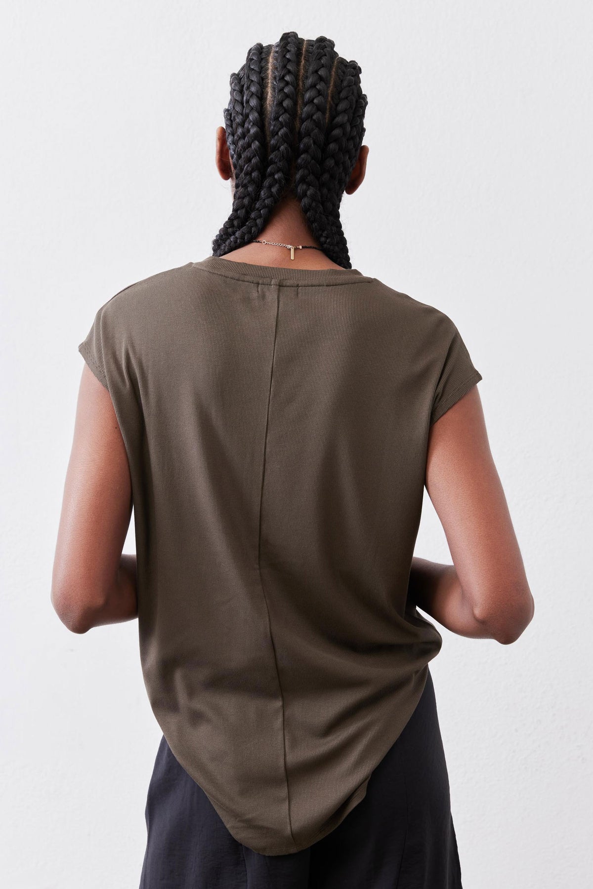 Olive crewneck tee back view with center seam and short sleeves over dark pants