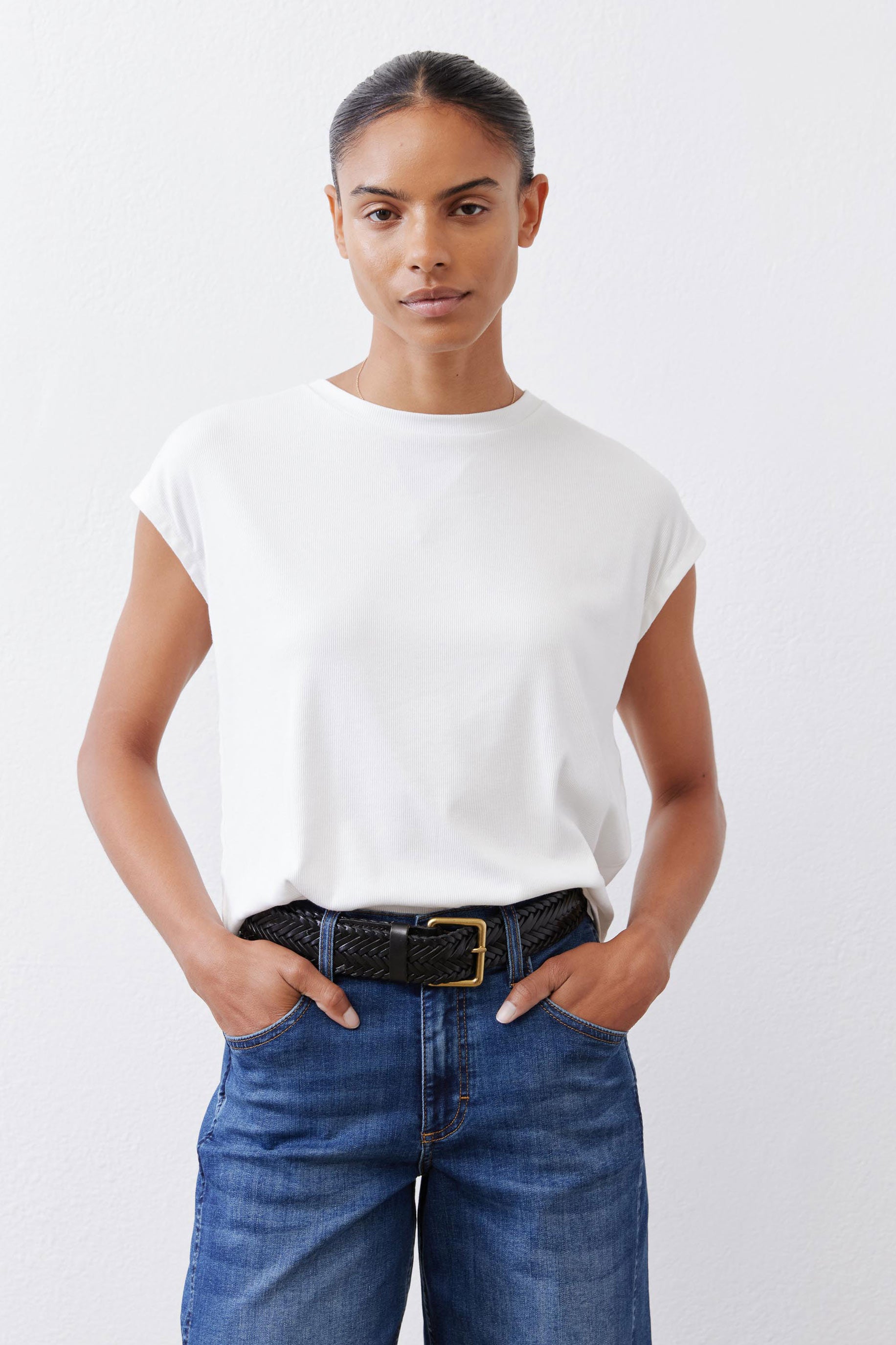 White ribbed crewneck tee with short sleeves, tucked into waistband