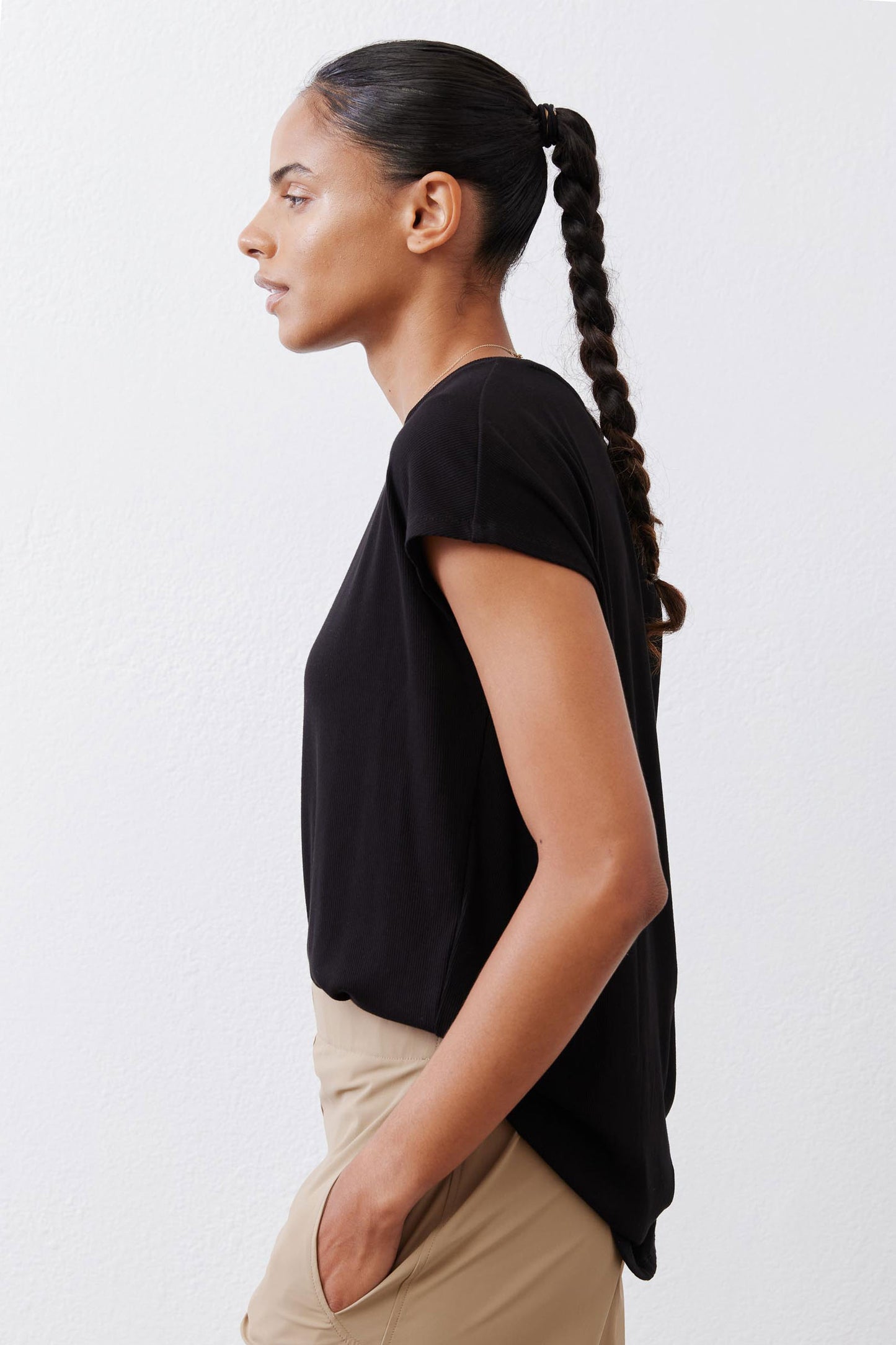 Black ribbed tuck-in tee with short sleeves, tucked into beige pants