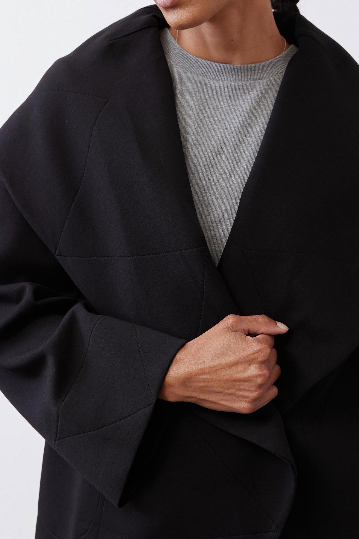 Black shawl-collar wrap coat detail with overlap front and matte finish