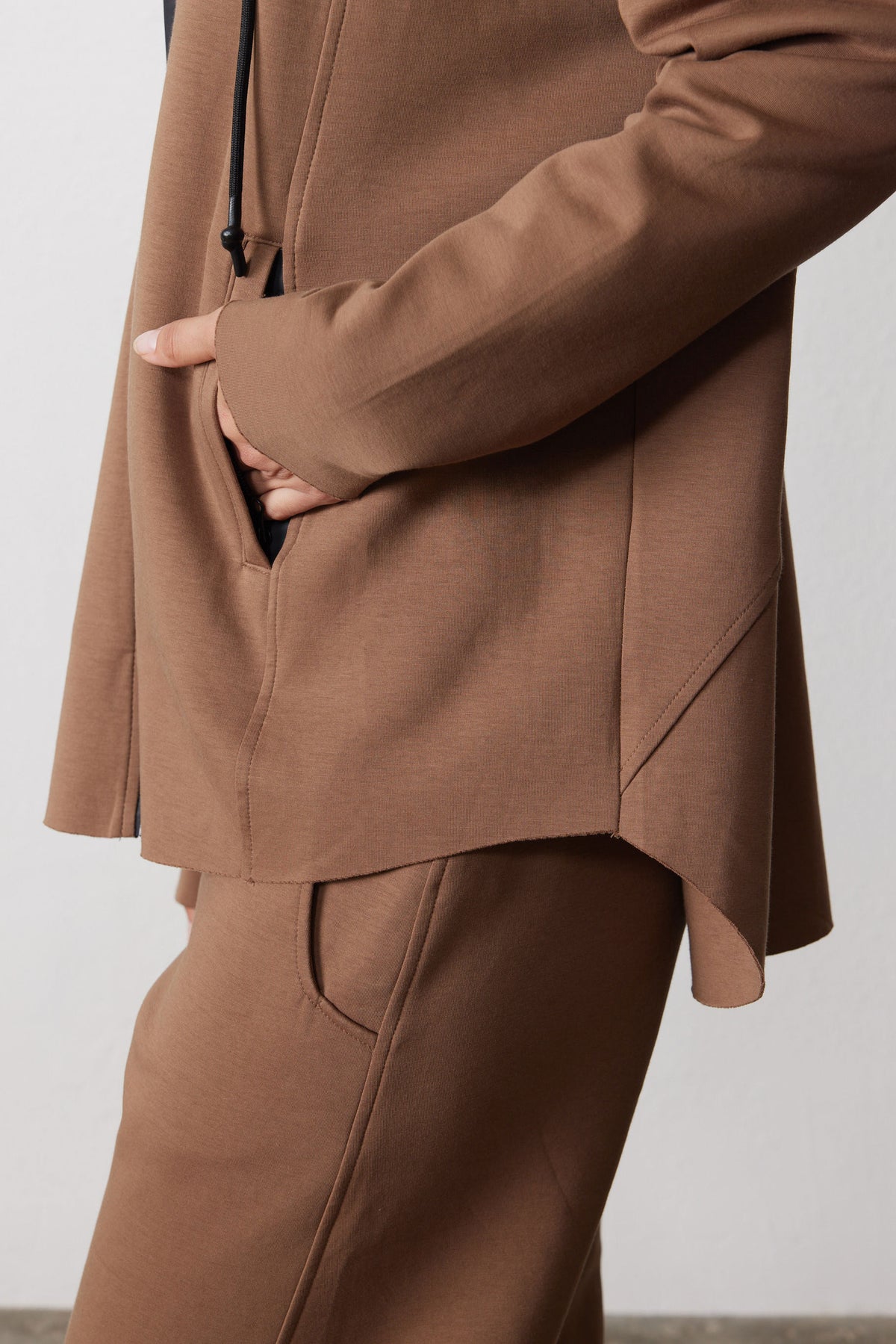 Close-up of the mocha scuba hoodie's front pocket, long cuff, and curved hem.
