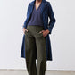 Deep blue V-neck sleeveless tank top under long navy jacket and olive trousers