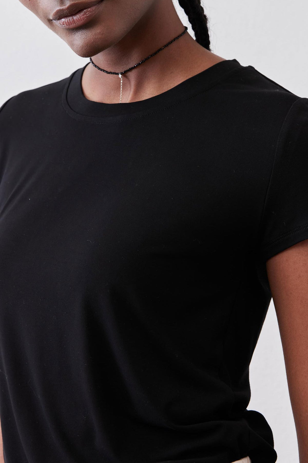 Black crew neck short-sleeve tee close-up, smooth knit and curved neckline