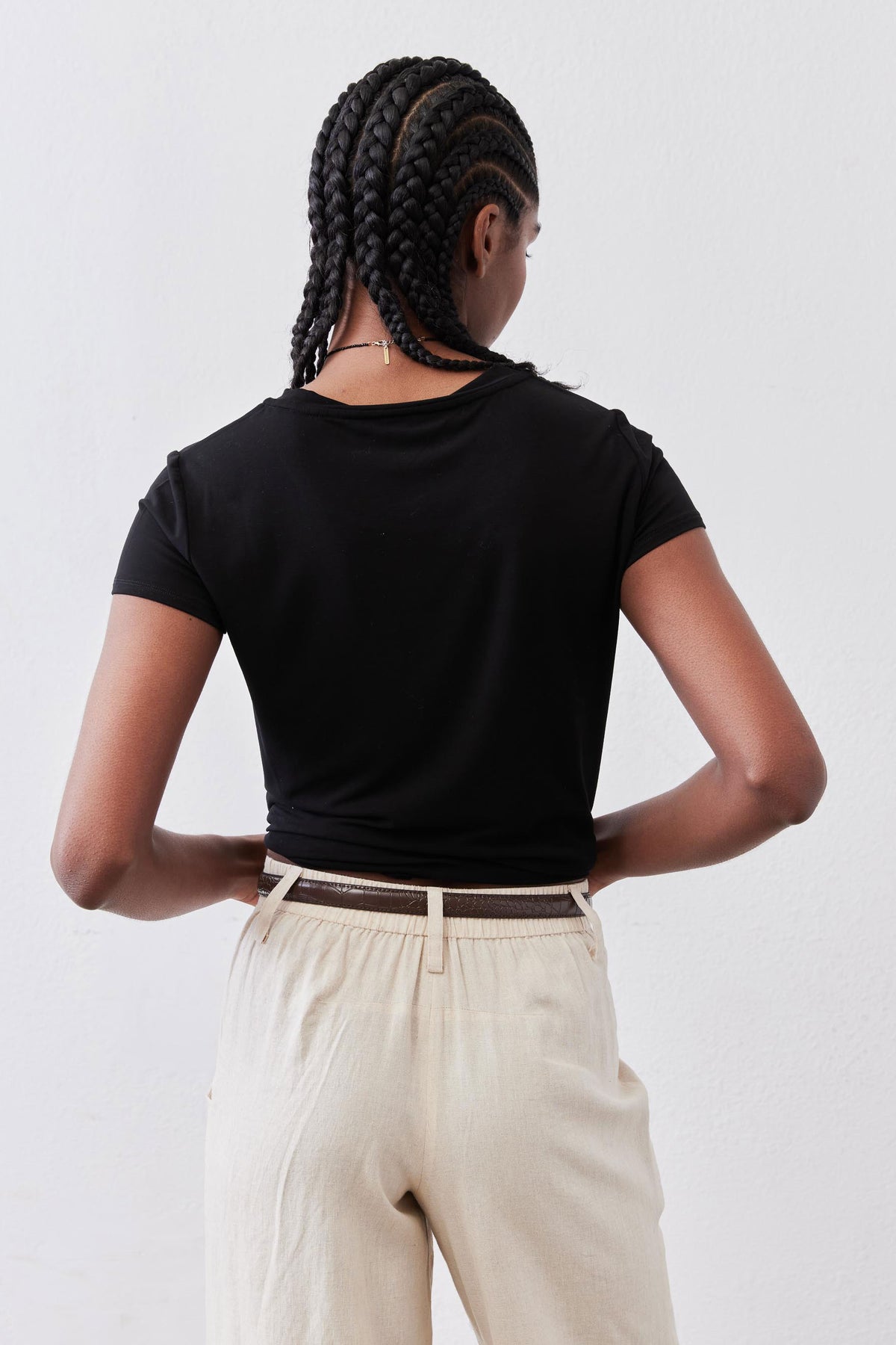 Black short-sleeve crew neck tee, back view with even sleeve hems