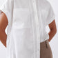 White poplin button-down blouse close-up with pointed collar and front patch pocket