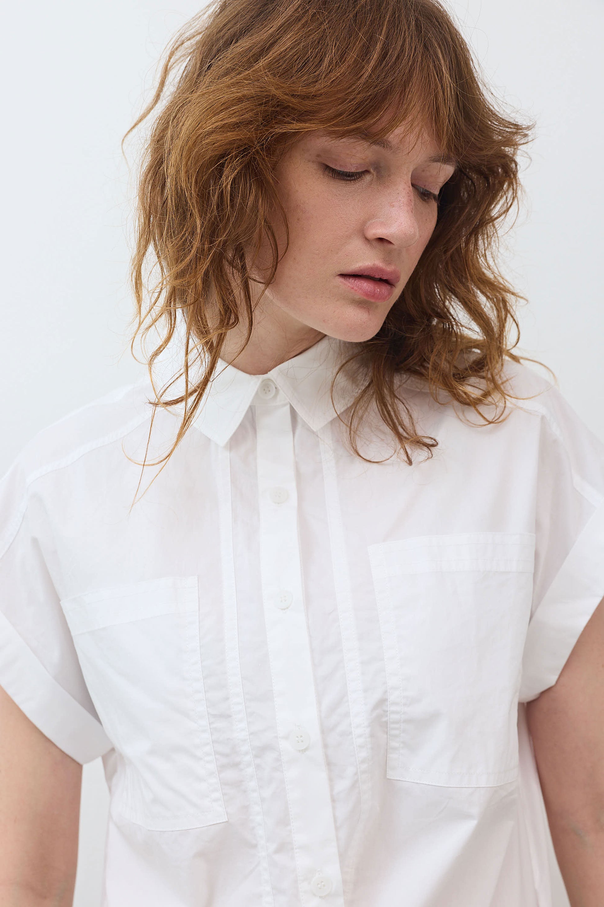 White poplin button-down blouse with pointed collar, front buttons, and chest pocket
