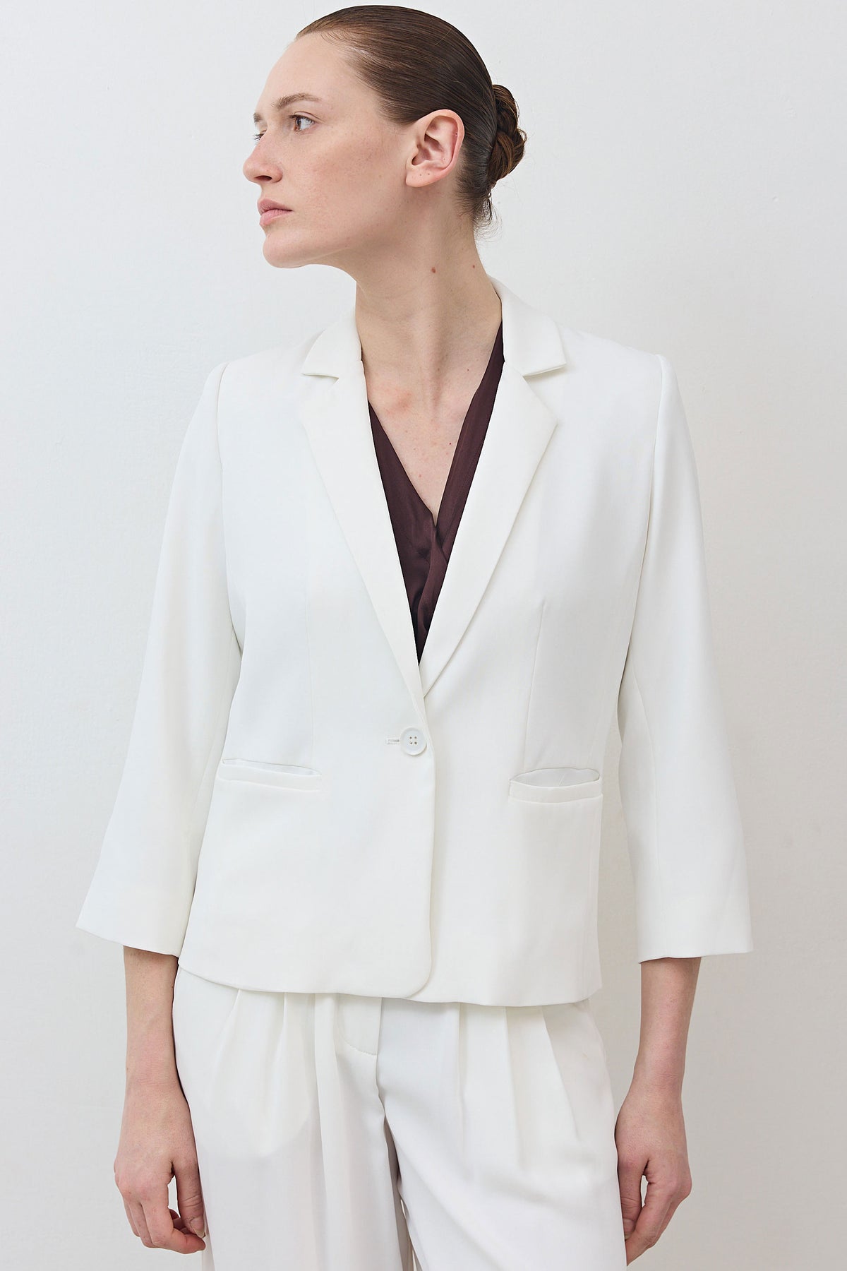 White shrunken blazer with notch lapel, button closure, and chest welt pocket.