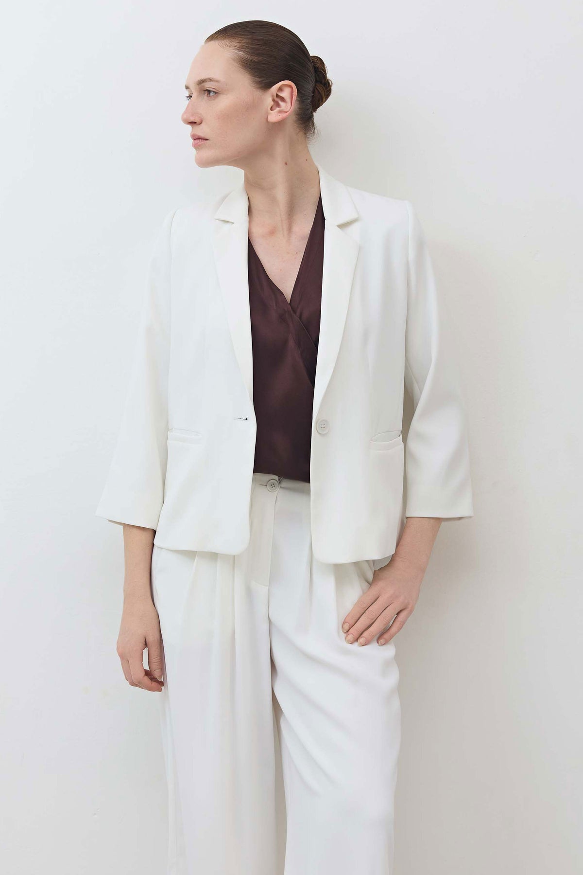 White shrunken blazer with structured shoulders, notch lapel, and 3/4 sleeves.