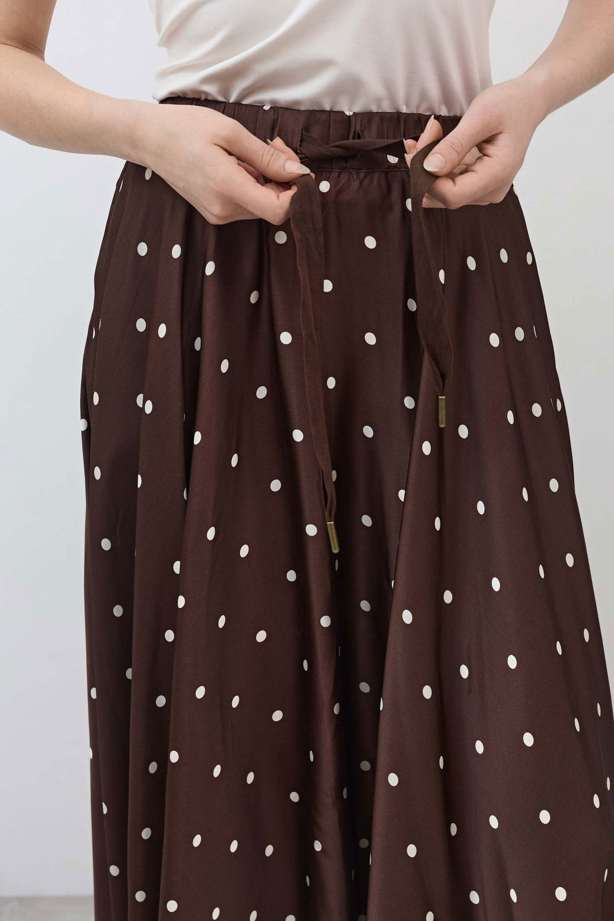 Brown skirt waistband with white dots, button detail, and elastic pull-on top