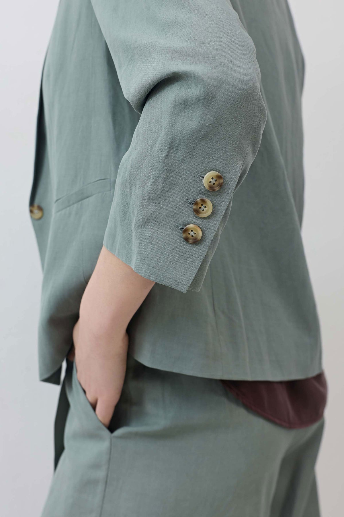 Chinois green blazer sleeve closeup, buttoned cuffs with fabric-covered buttons