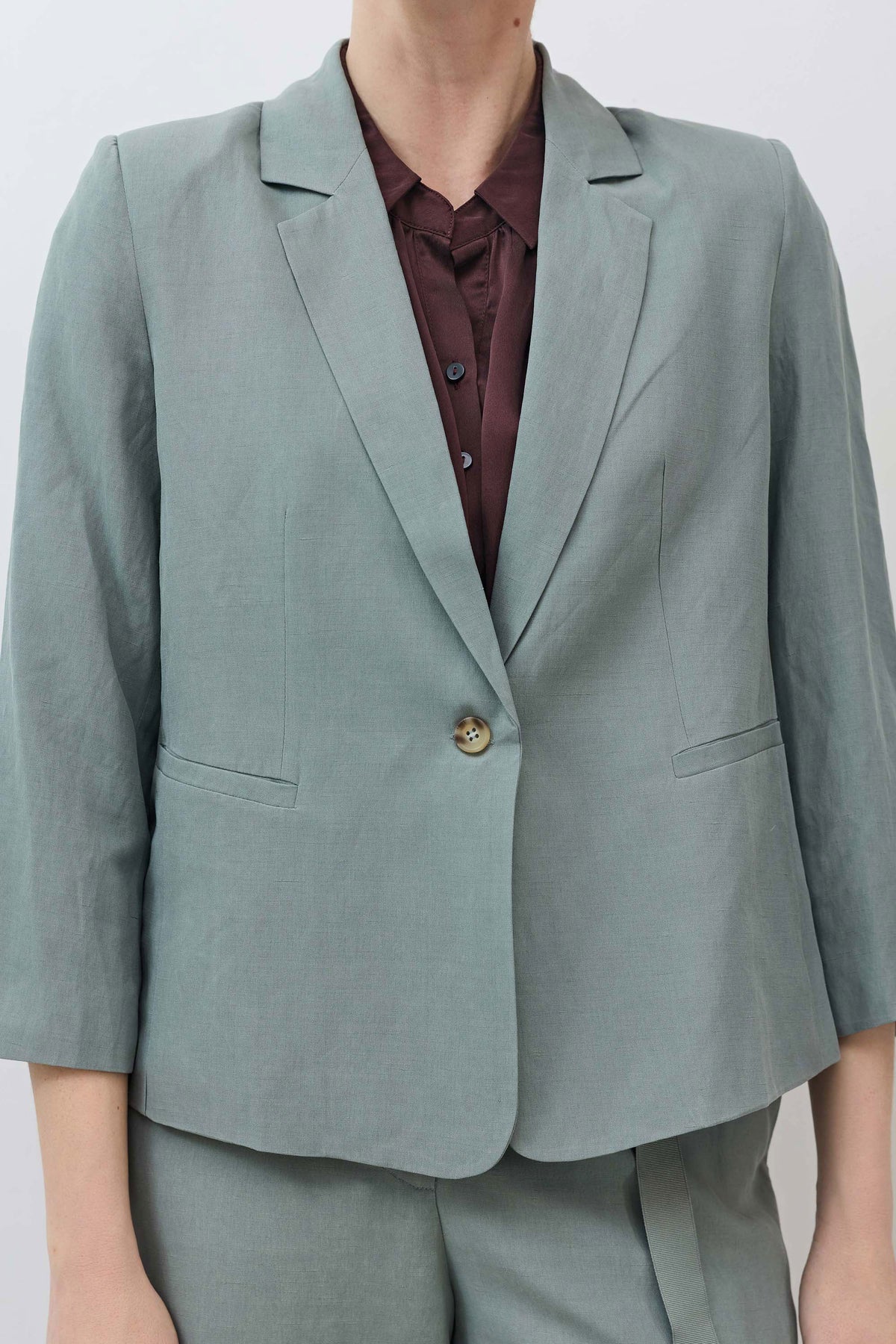 Chinois green blazer closeup, notch lapel, gold-tone button, patch pockets