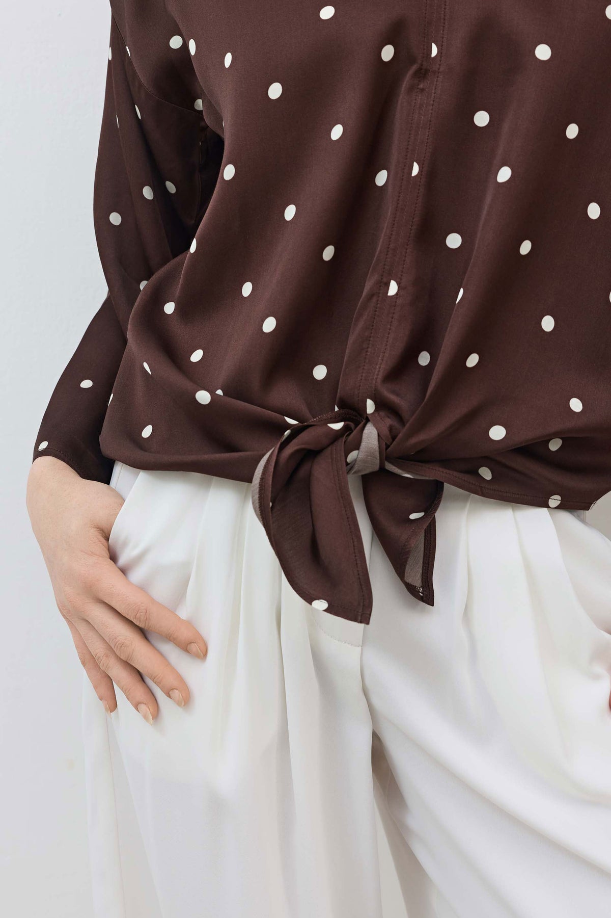 Silky tie-front blouse detail: brown with white polka dots, tied bow at waist