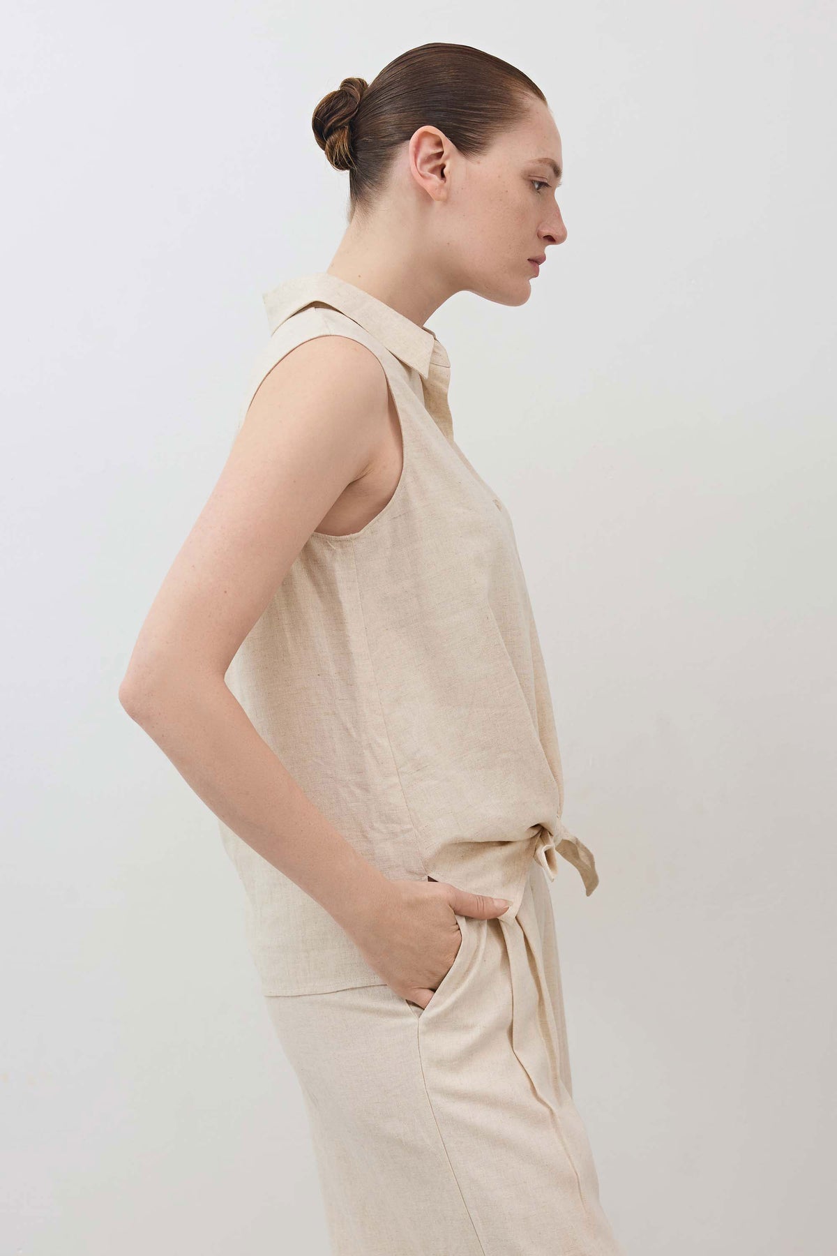Oatmeal sleeveless button-down top with collar and waist tie at side