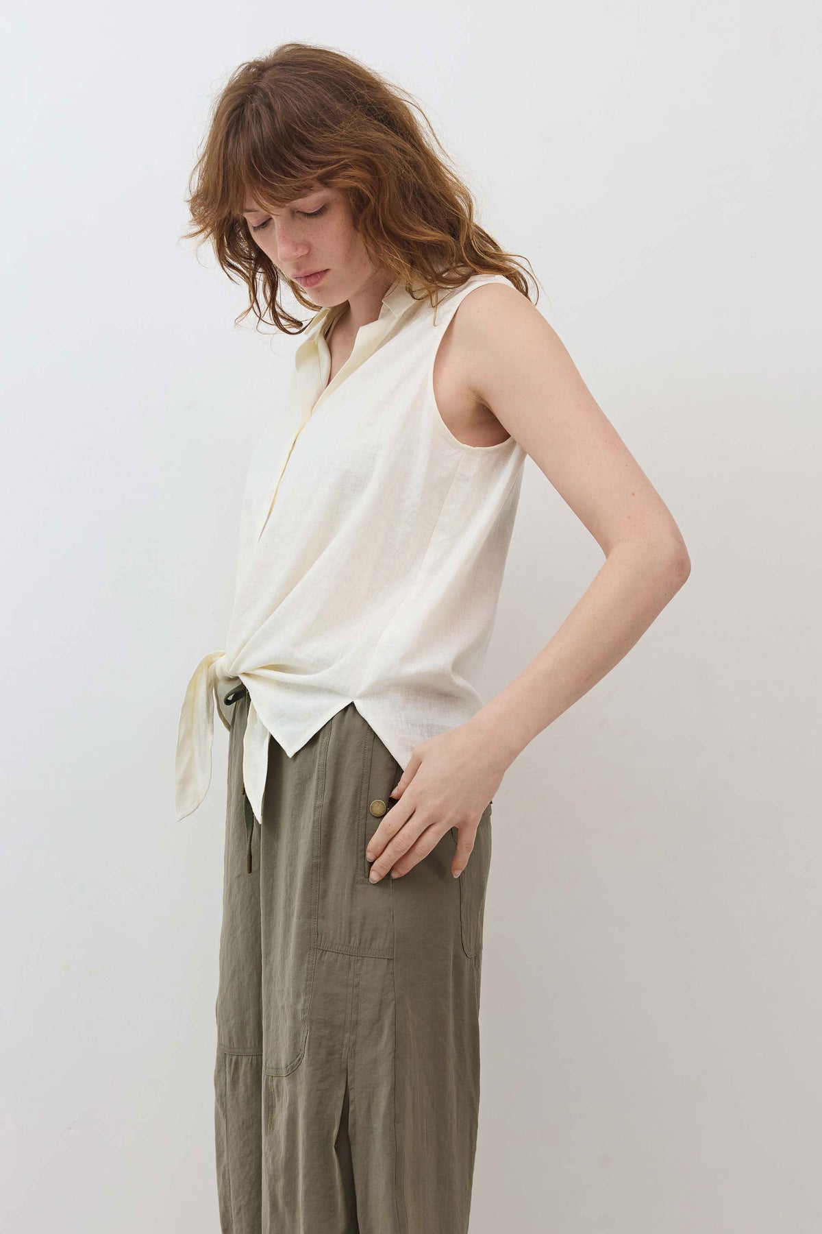 Ivory sleeveless tie-front button-down shirt with side tie detail at hem