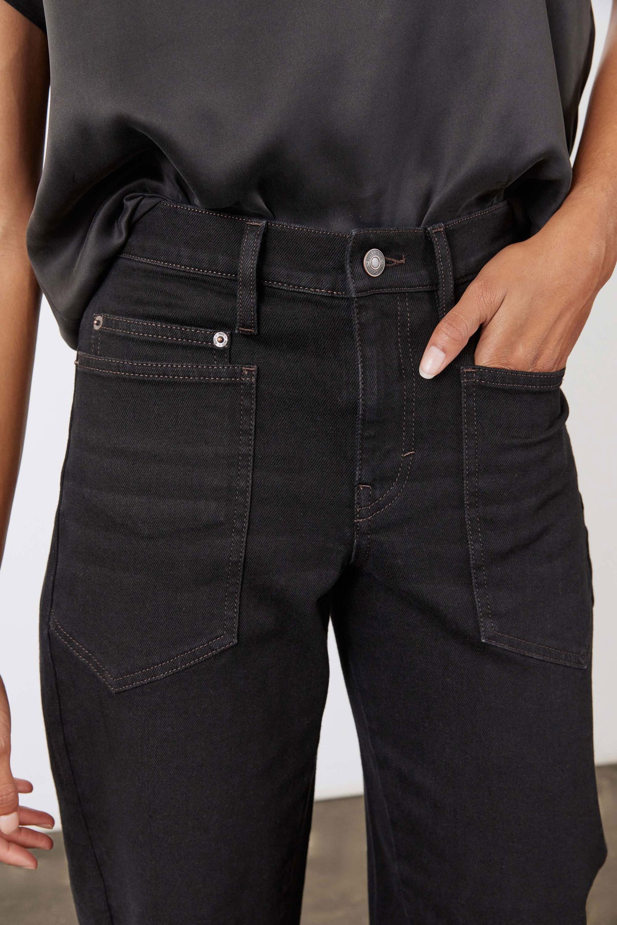 Black slouchy jeans close-up of waistband with belt loops and front pockets